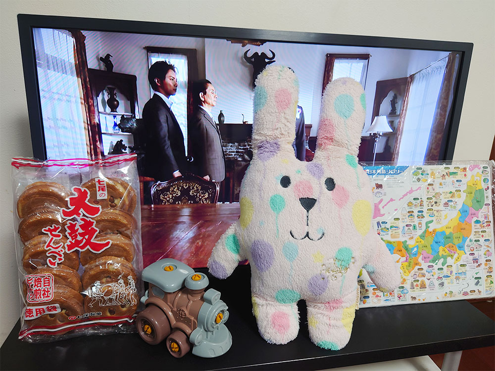 テレビ、せんべい、ぬいぐるみ、組み立ておもちゃと地図が置かれた写真